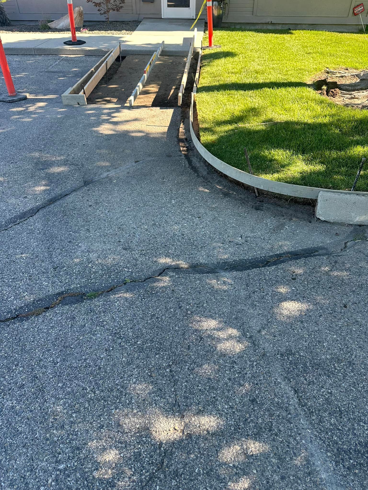 A concrete ramp is being built in the driveway of a house.