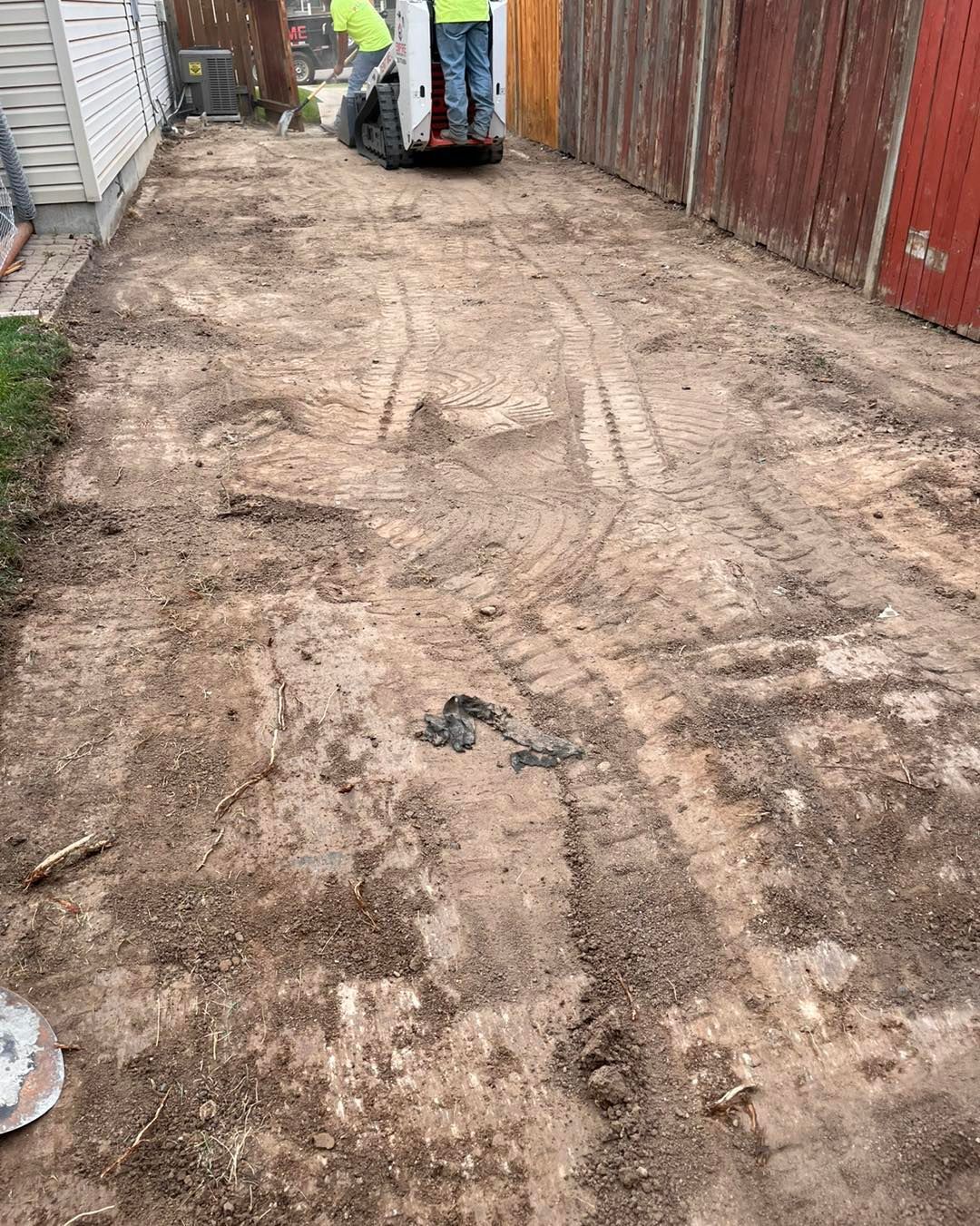 A man is using a shovel to remove dirt from a driveway.