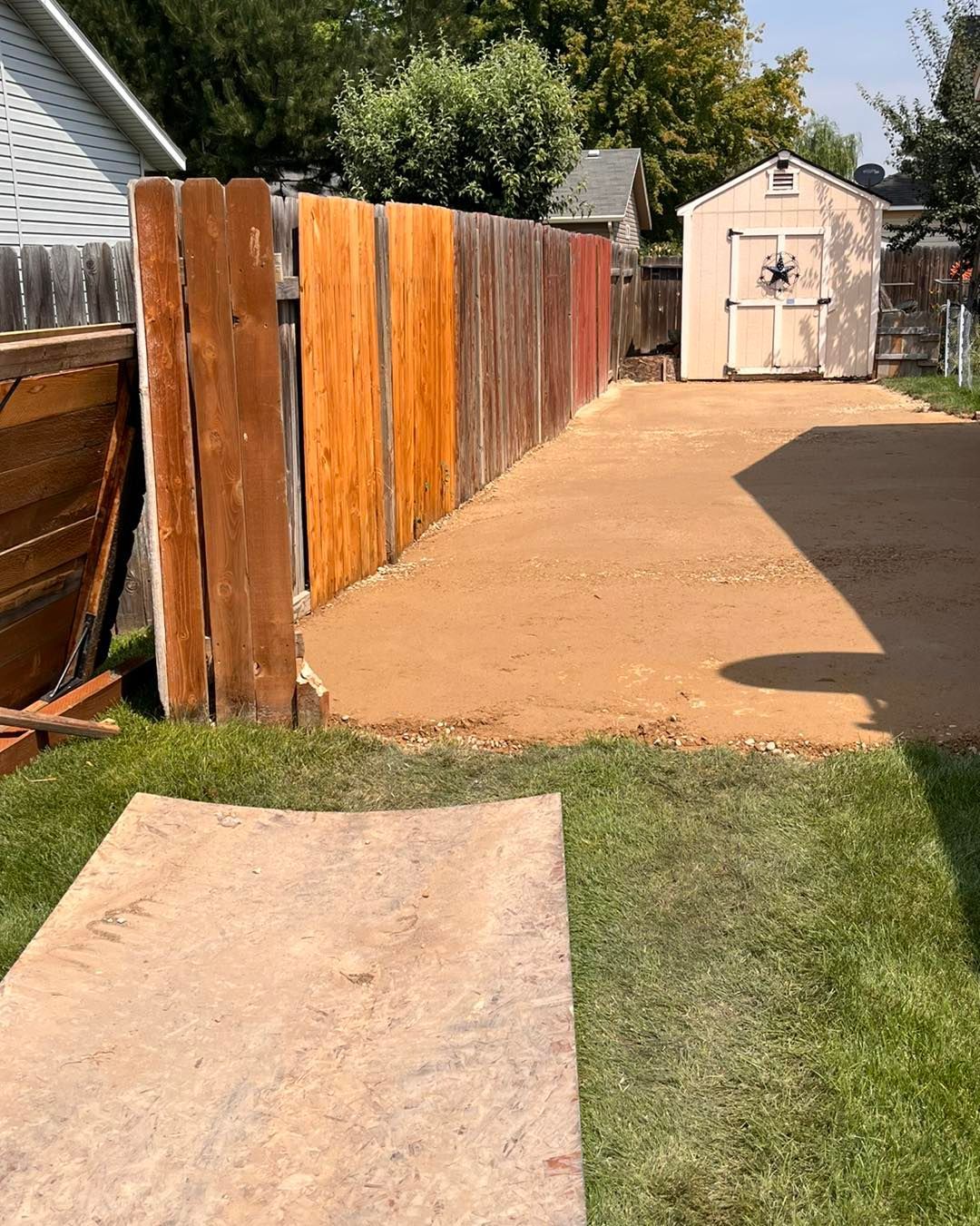 A wooden fence with a shed in the background