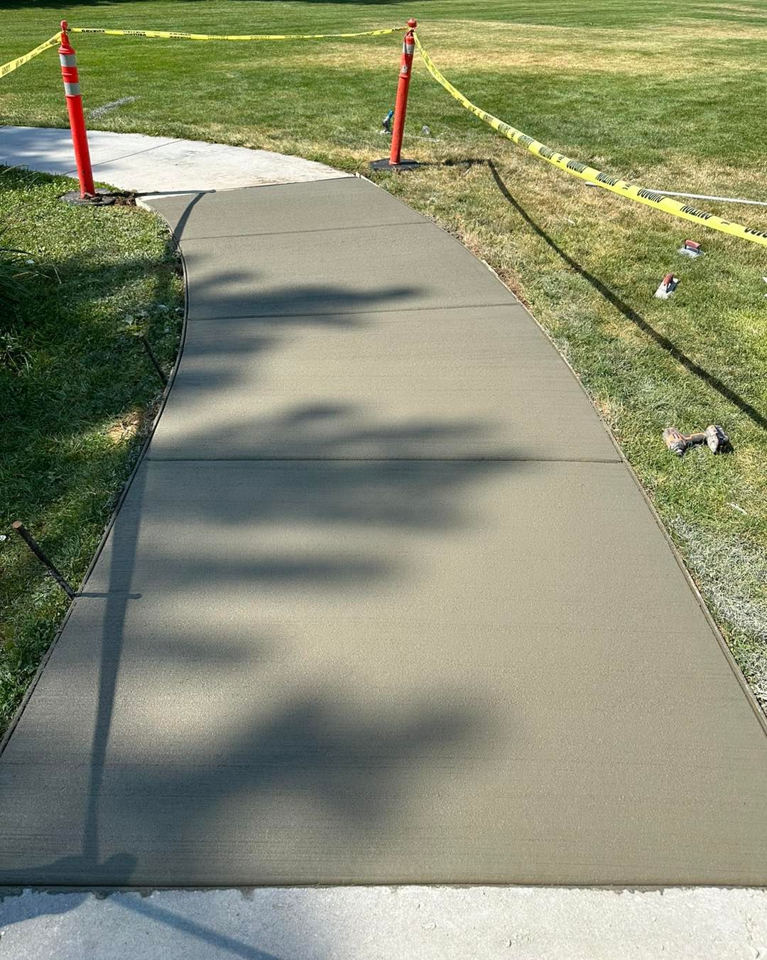 A concrete walkway leading to a grassy field