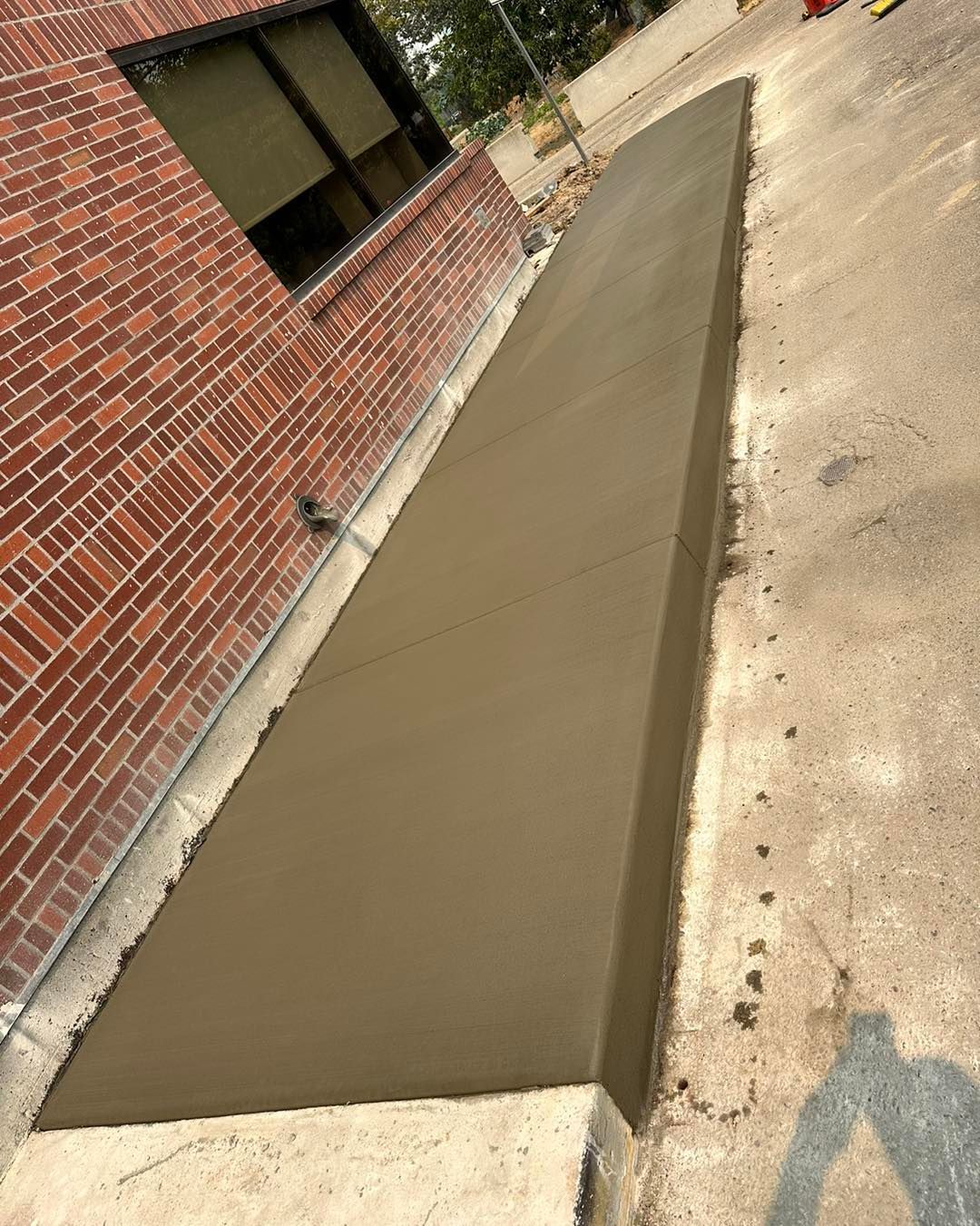 A concrete walkway is being built in front of a brick building.