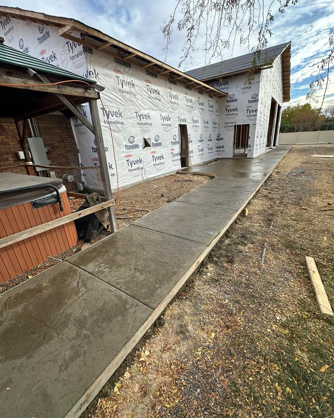 A walkway leading to a house under construction with a hot tub in the background.