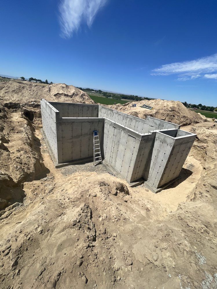 A large concrete structure is sitting in the middle of a dirt field.