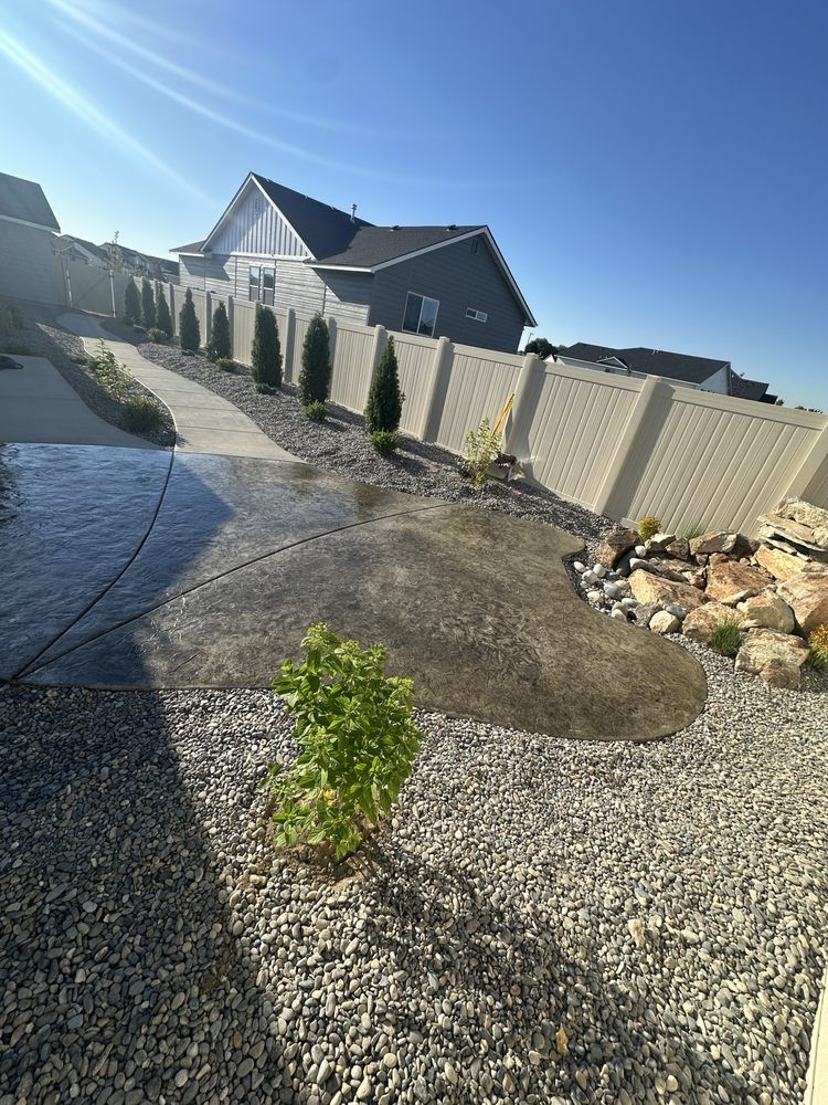 A white fence surrounds a gravel yard with a house in the background.