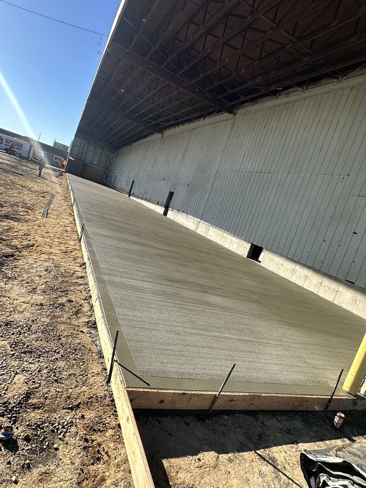 A concrete walkway is being built in front of a large building.