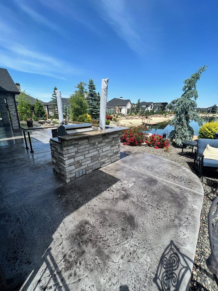 A patio with a brick counter top and a view of a lake.
