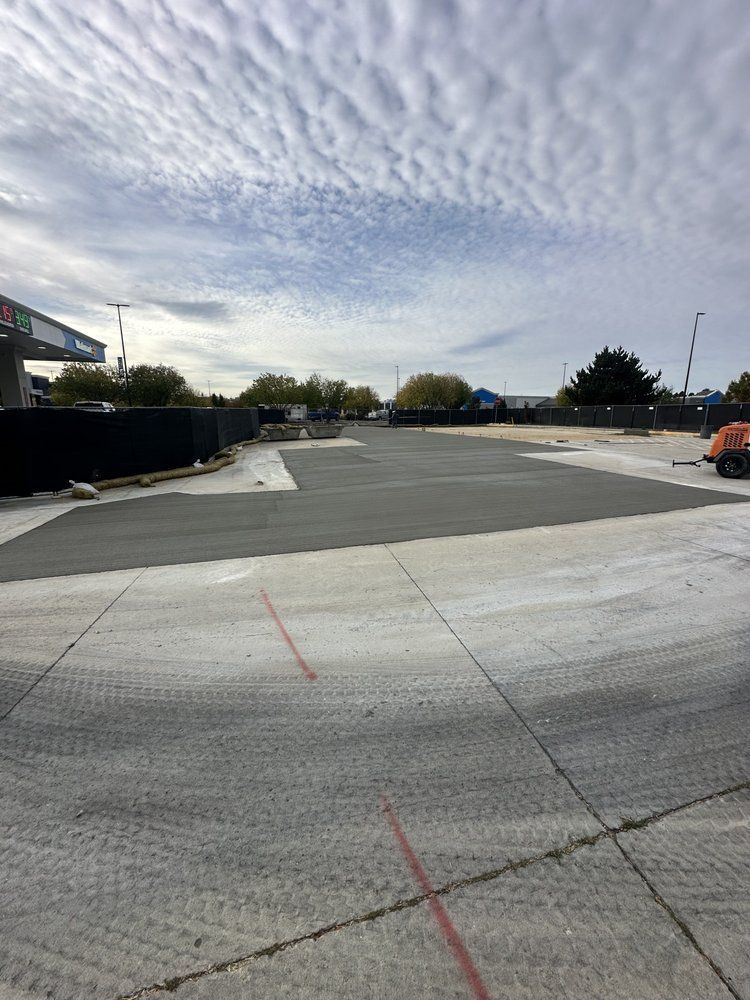 A large empty parking lot with a gas station in the background.
