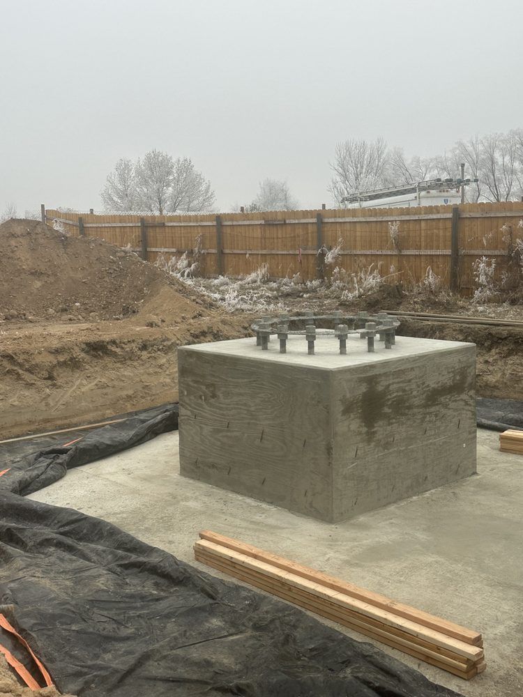 A concrete block is sitting in the middle of a dirt field next to a wooden fence.