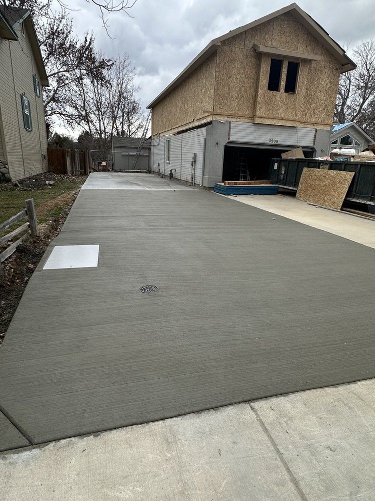 A concrete driveway leading to a house under construction.