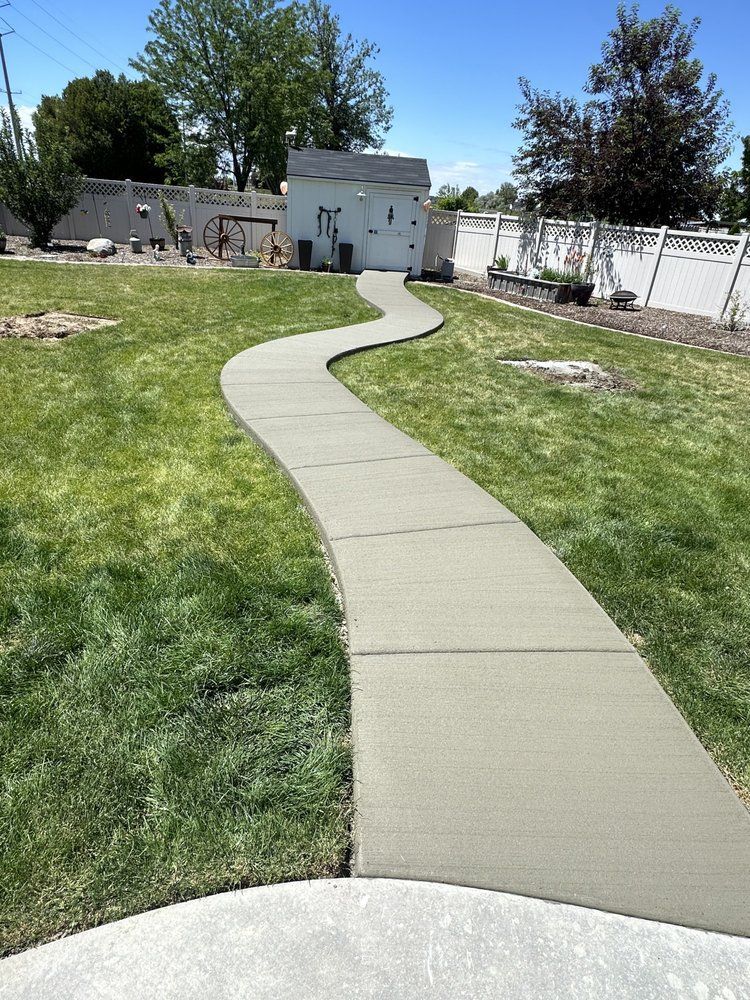 A concrete walkway going through a lush green yard.
