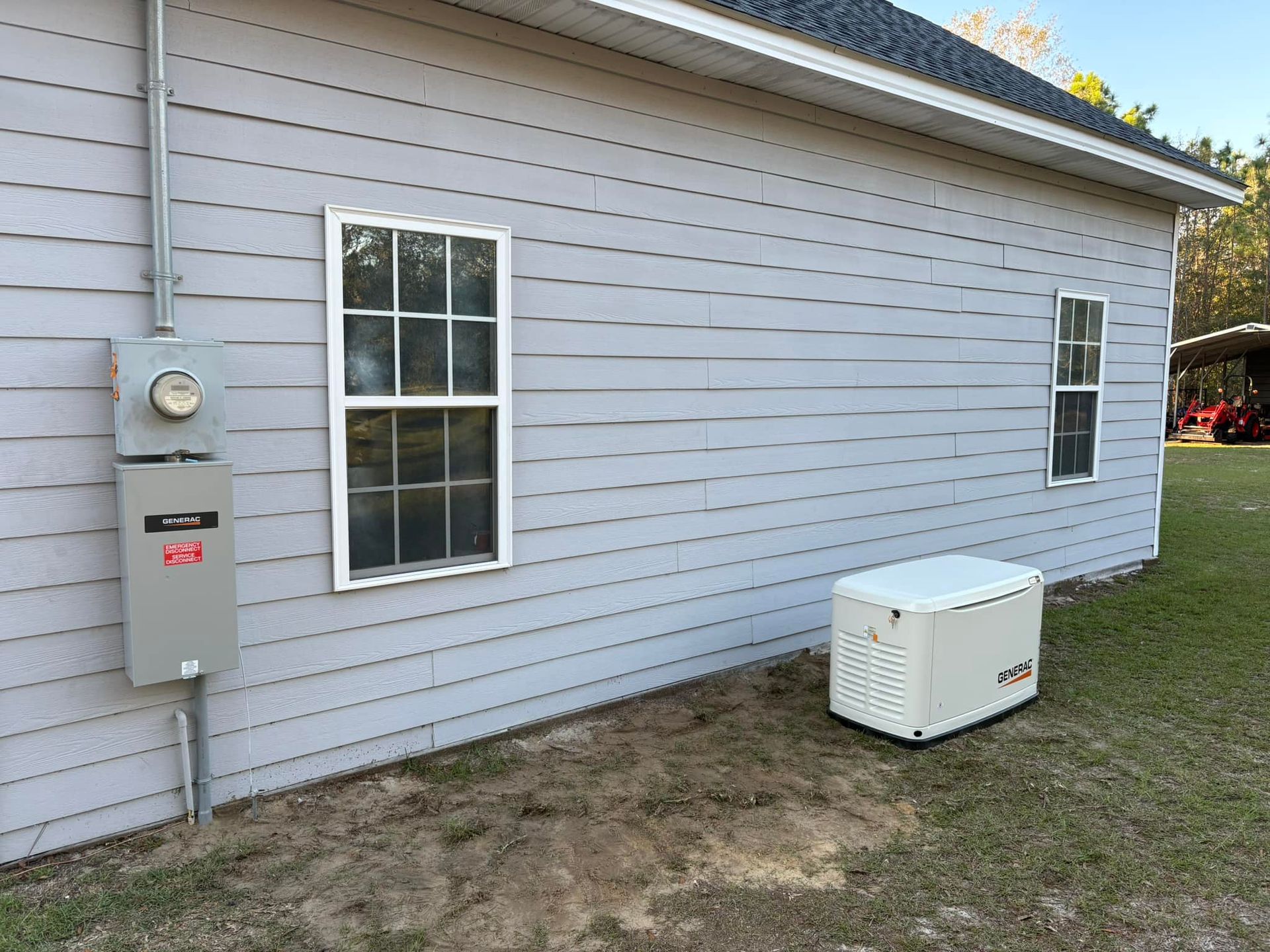 Gray house exterior with power meter, windows, and a white generator on the ground.