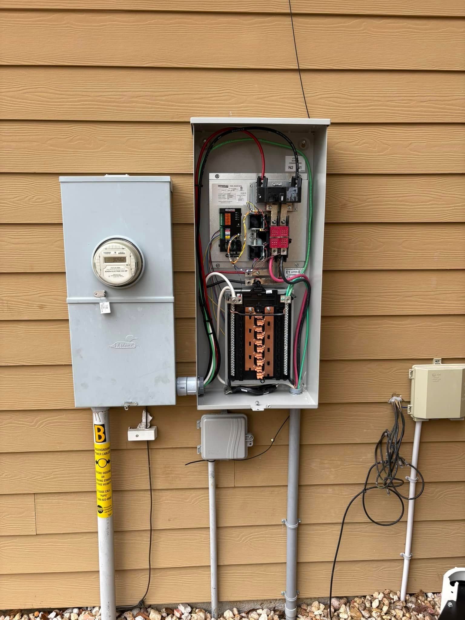 Exterior electrical panel on a brown-sided house, with a meter box, conduit, and wiring visible.