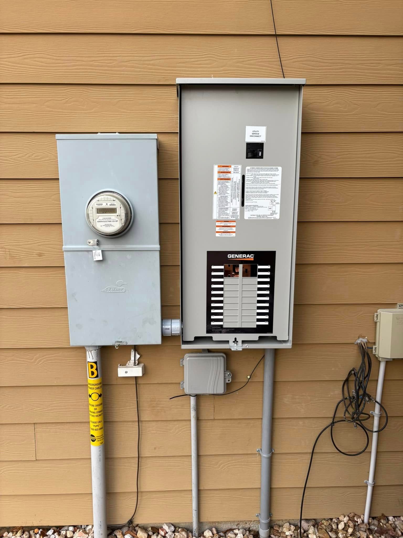 Exterior electrical panel and meter box on a brown-sided building. Gray metal boxes, gray conduit, and yellow sticker.