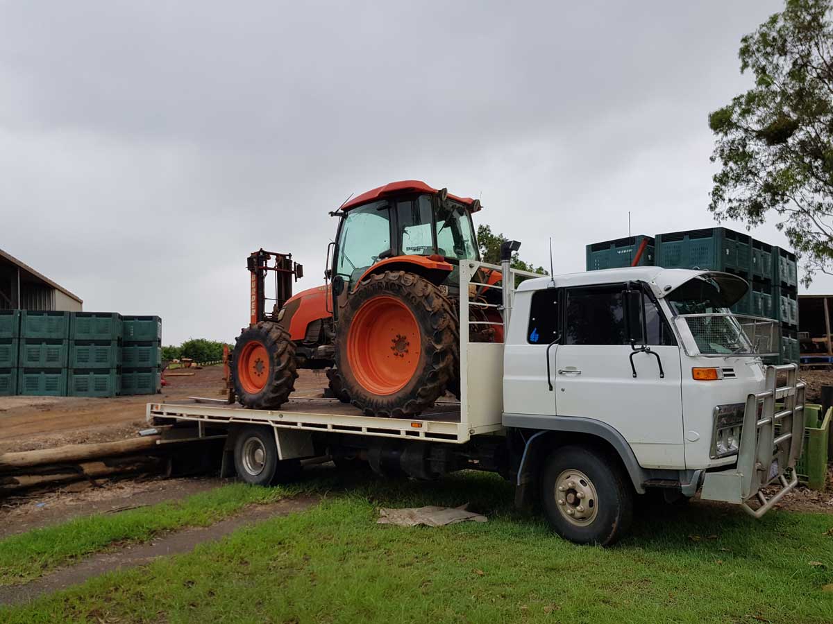 A tractor is sitting on top of a flatbed truck.