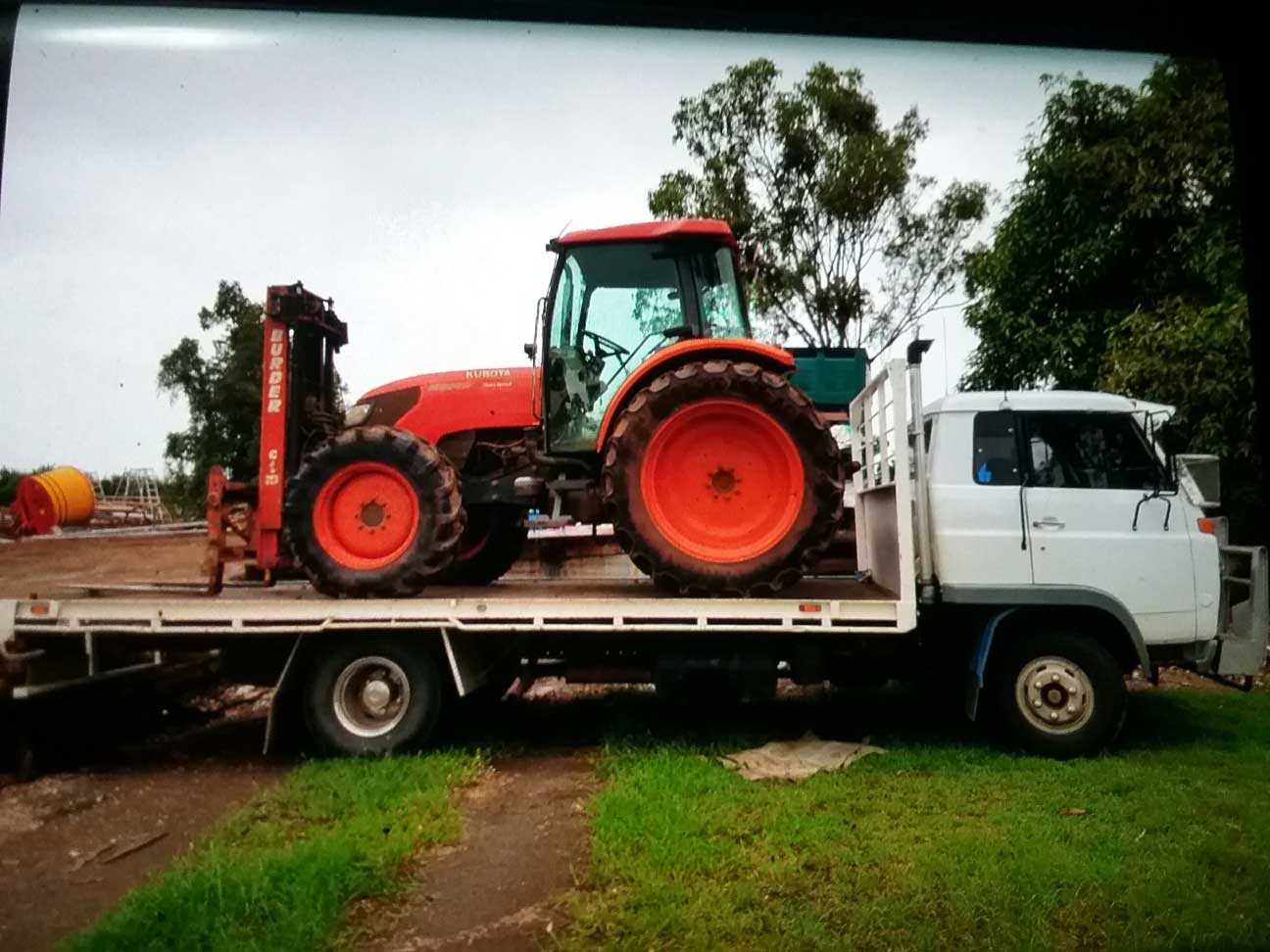 A tractor is on the back of a flatbed truck
