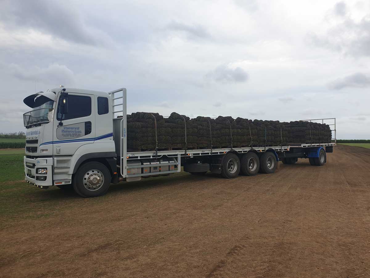 A large white truck is parked in a dirt field.