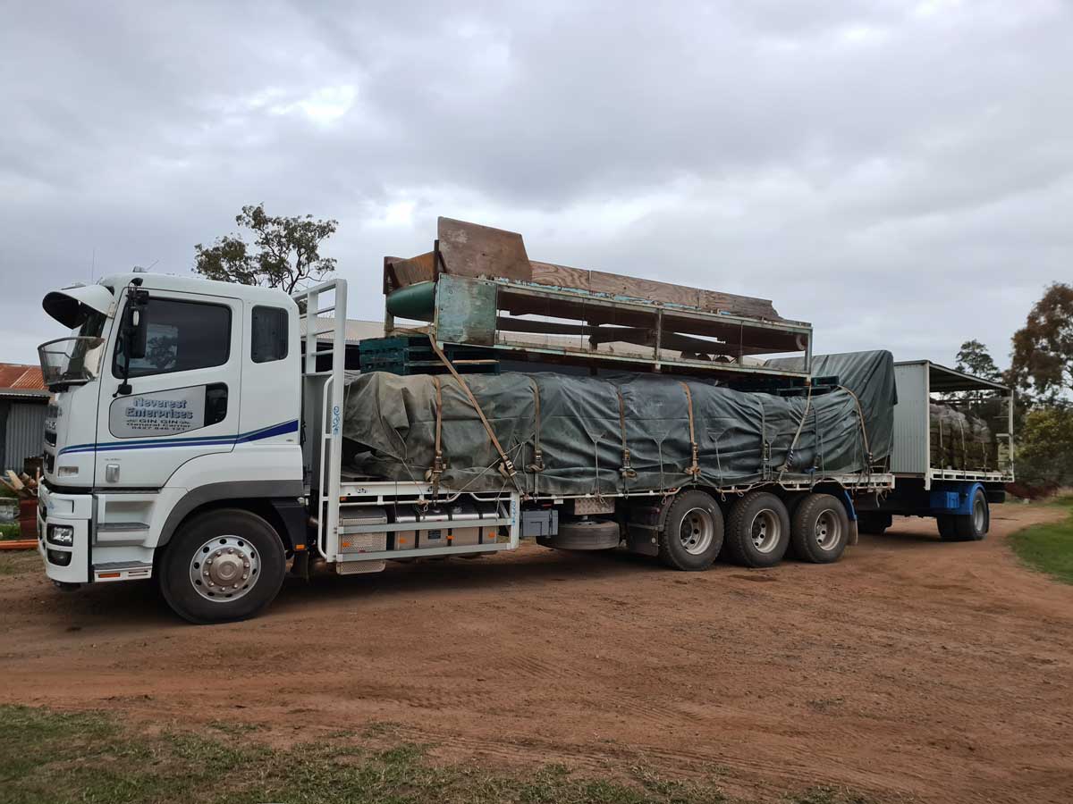 A white truck with a trailer is parked on a dirt road.
