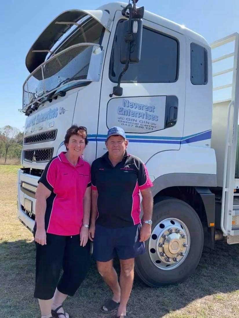 A man and a woman are standing in front of a truck.
