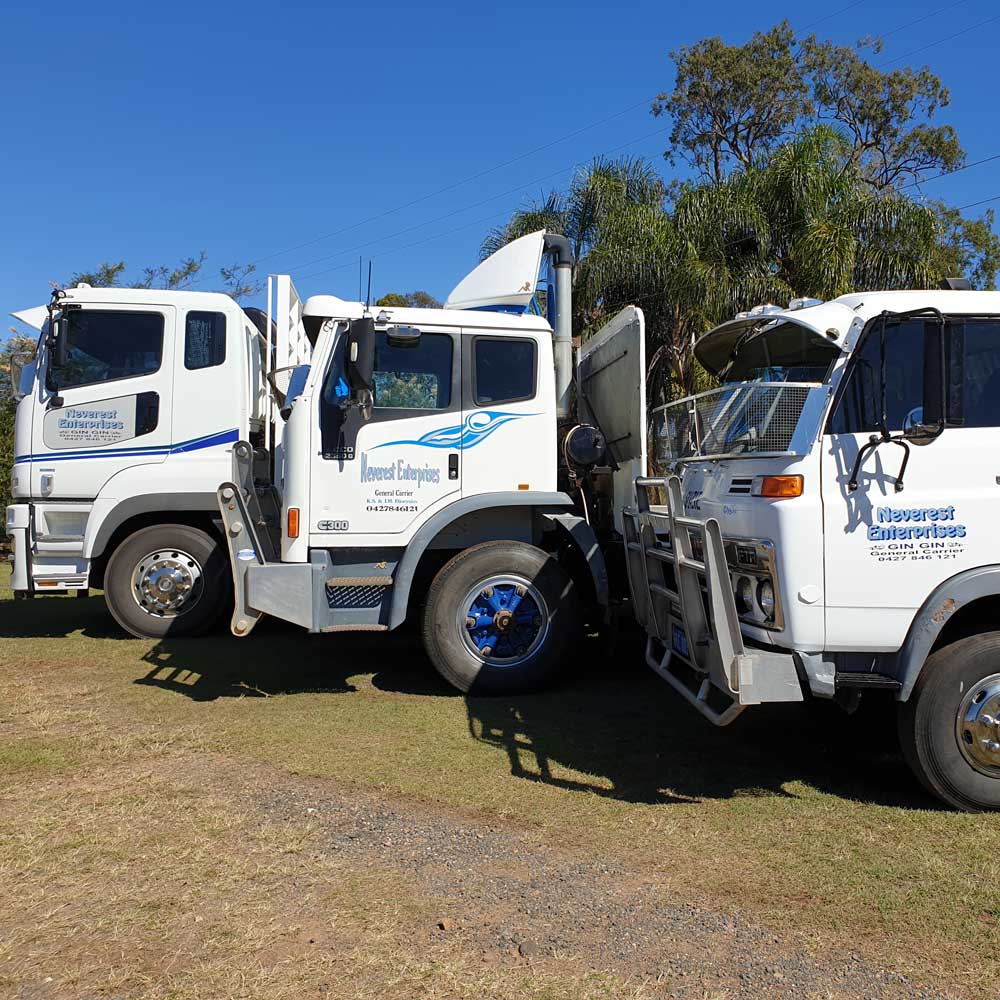 Two white trucks are parked next to each other in a grassy field