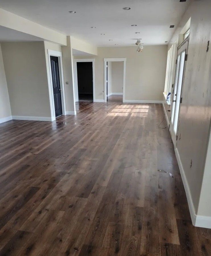 An empty room featuring dark wood flooring, light-colored walls, recessed ceiling lights, and multiple doorways.