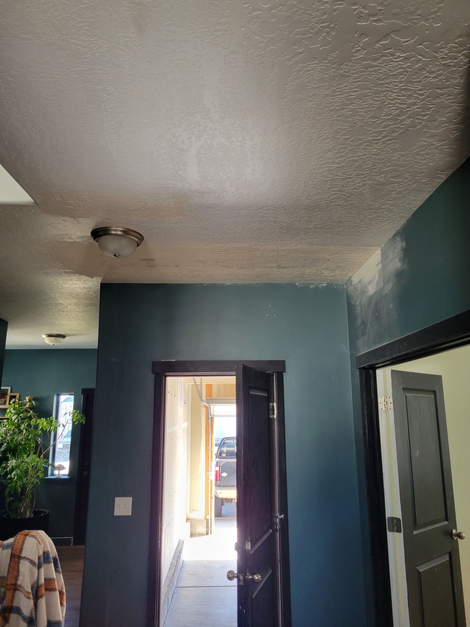 A view through a doorway into a room with dark blue walls, a textured white ceiling, and a dome light fixture.
