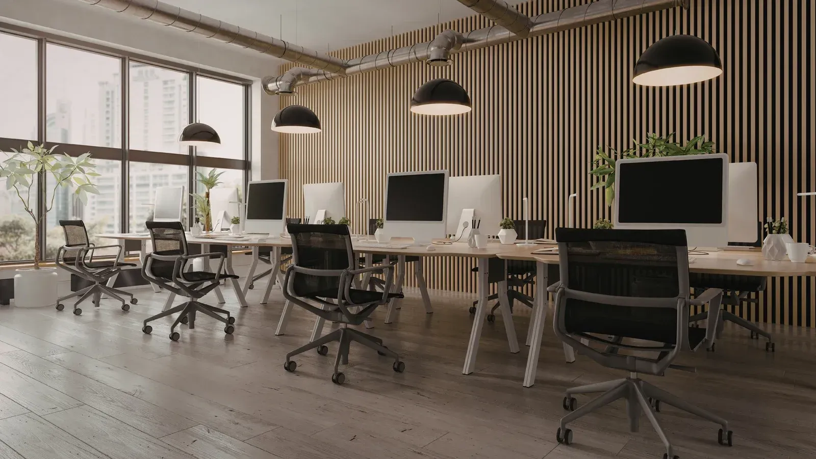 Modern office space with desks, chairs, and computers set against a slatted wood wall under pendant lighting.