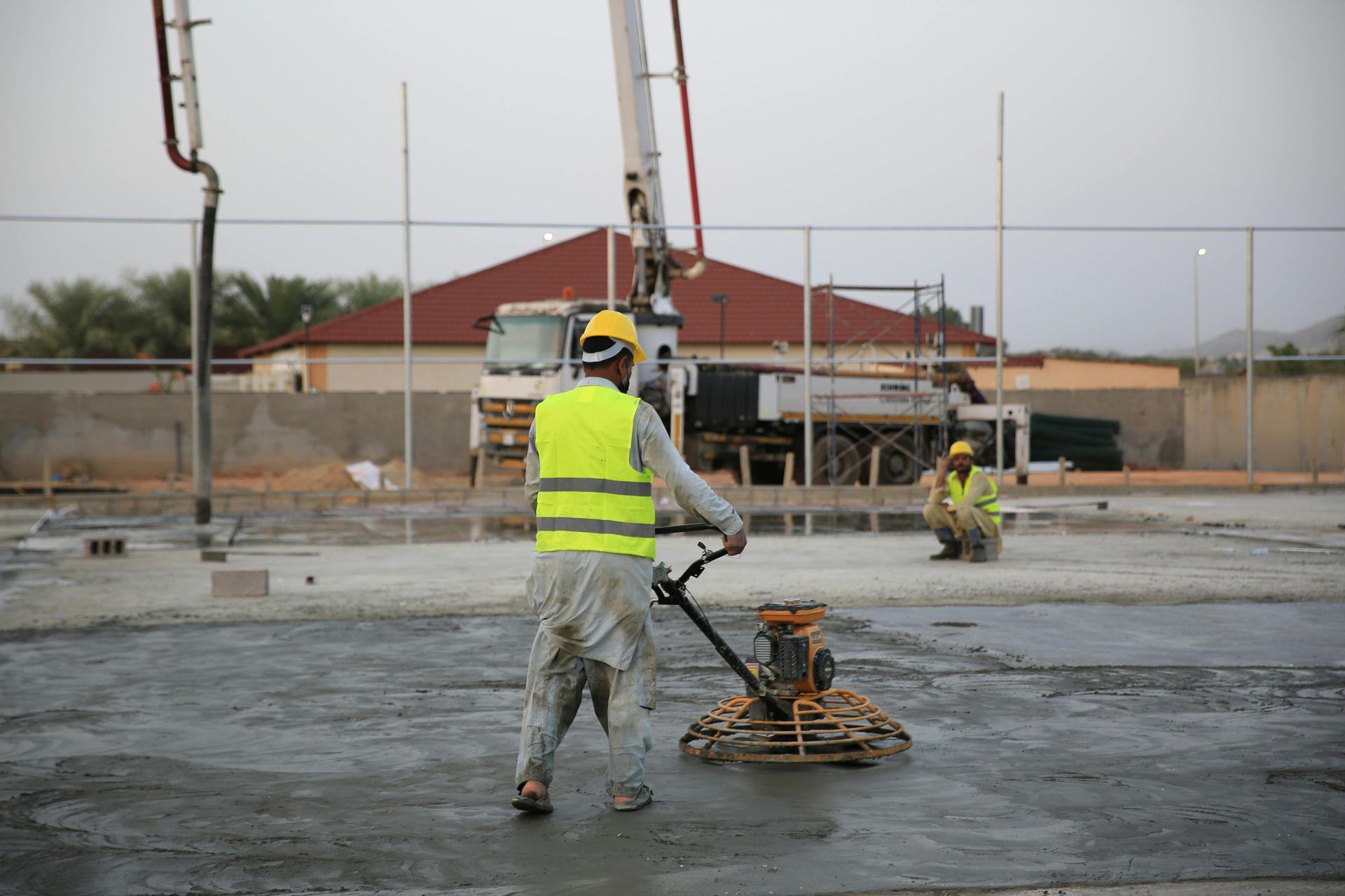 Construction workers smoothing wet concrete on a building site with a power trowel