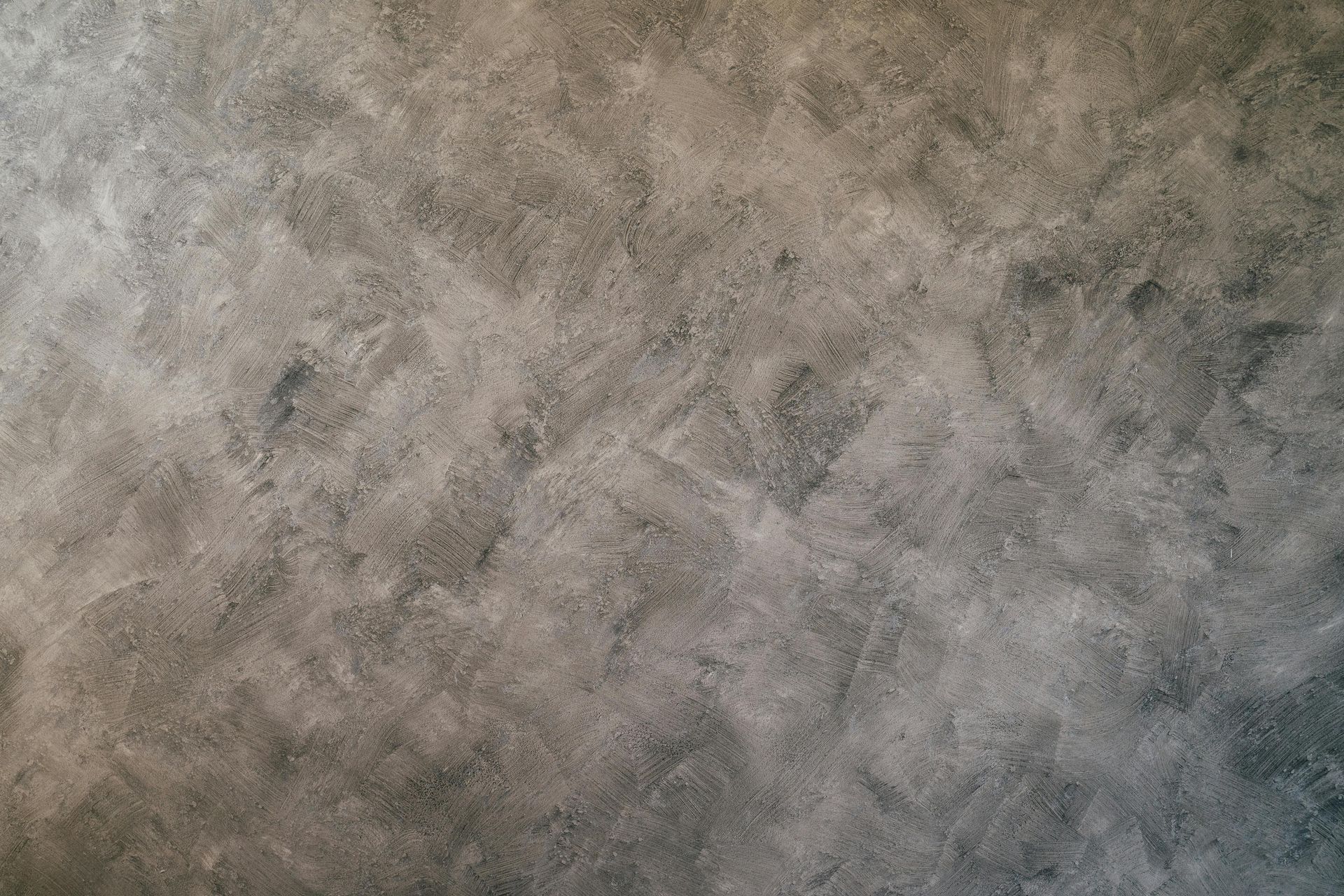 A textured surface with mottled grey and charcoal tones, resembling concrete or a decorative wall finish.