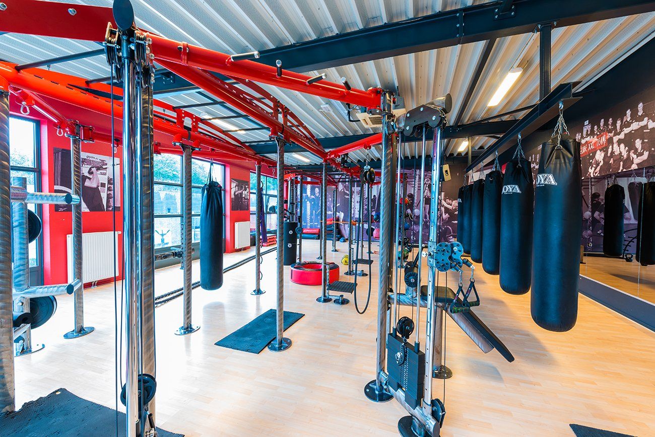 Een sportschool met veel bokszakken die aan het plafond hangen.