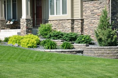 Aloha Concrete Pros custom tiered retaining wall installation cascading down a gently sloping hill in front of a house, highlighting expert craftsmanship in retaining wall solutions.