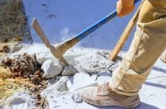 concrete contractor removing damaged concrete with a pickaxe