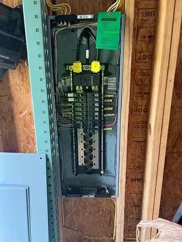 Electrical panel with multiple circuit breakers, mounted on a wooden wall with supporting metal frame.