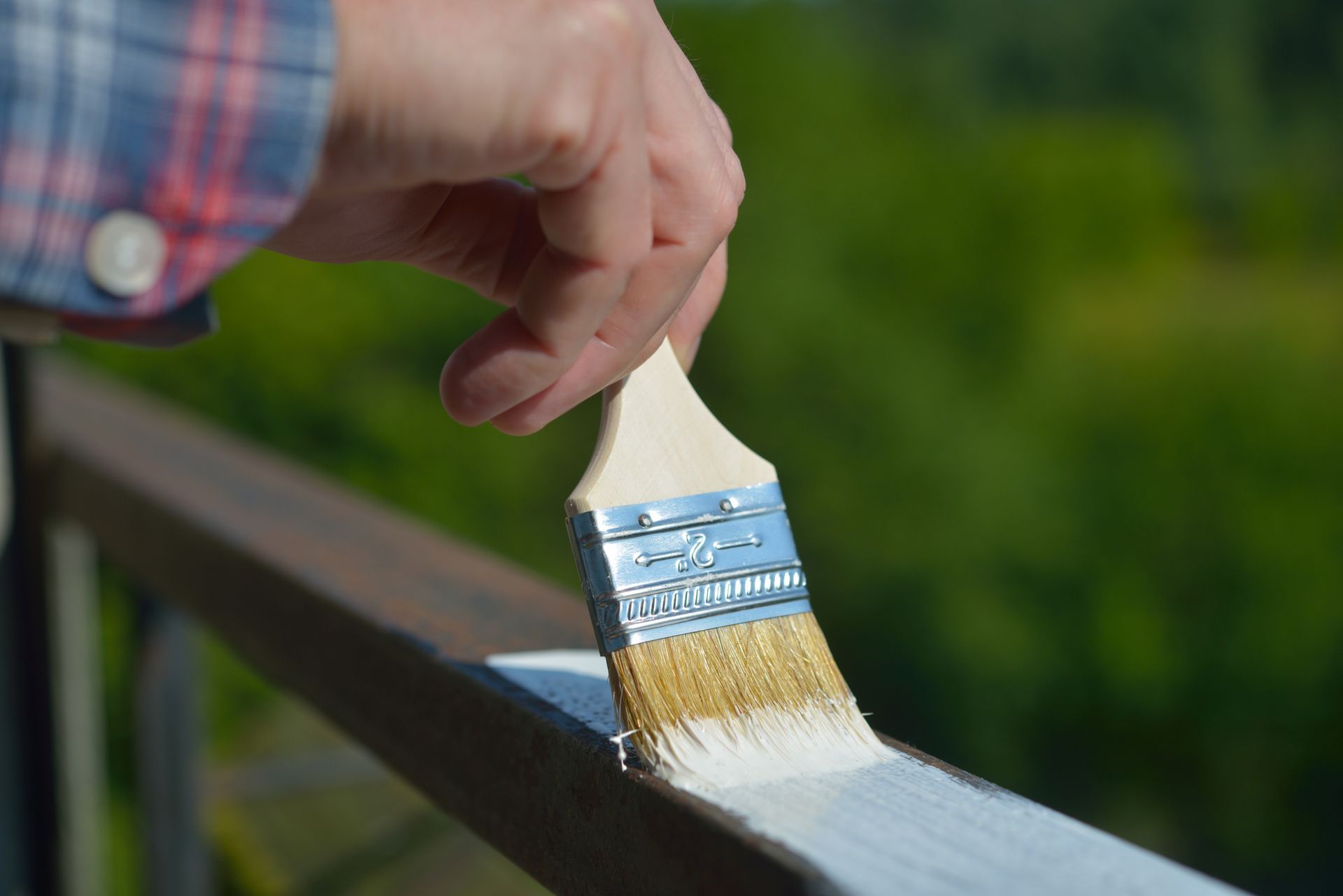 A person is painting a wooden railing with a brush.