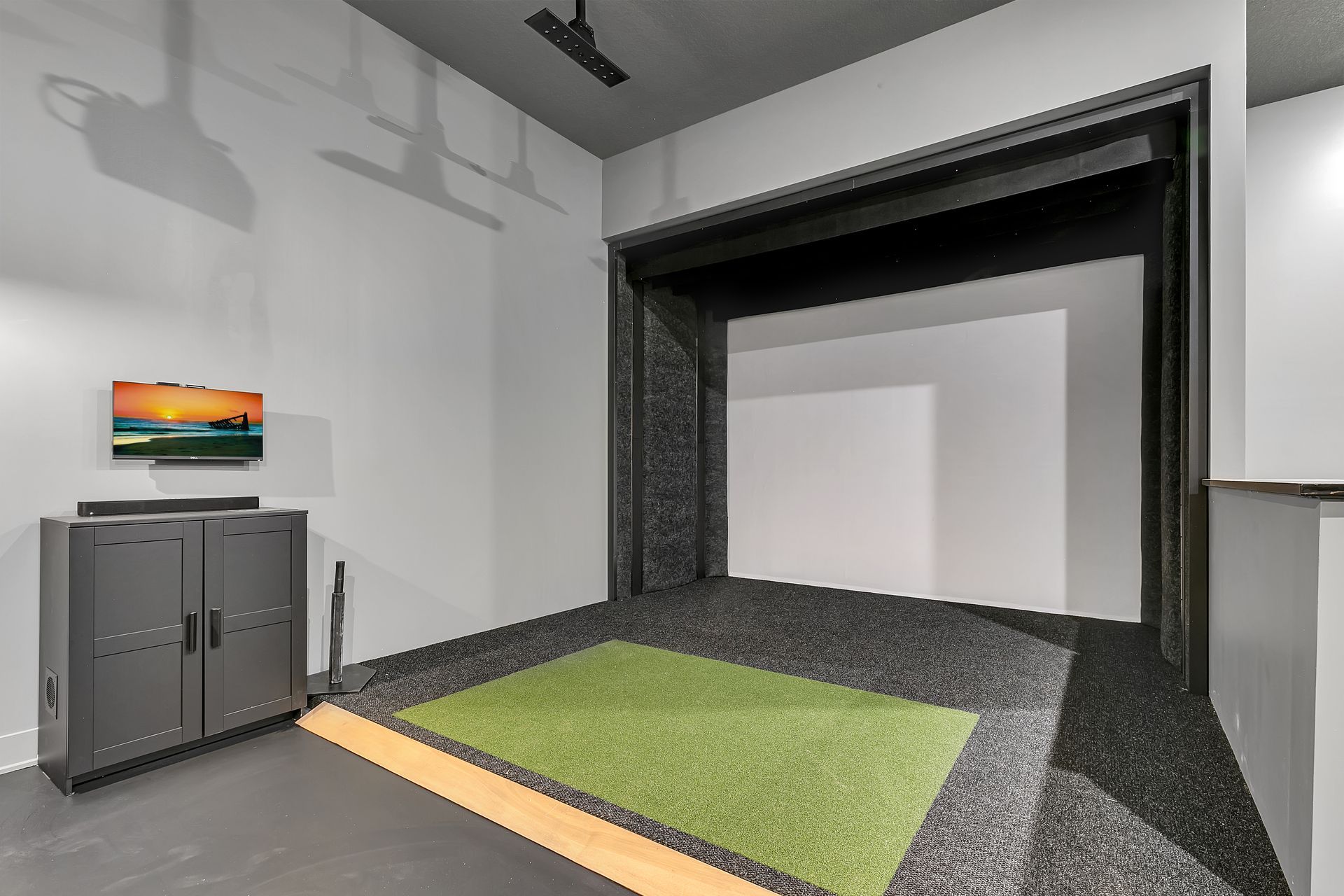 A room with a green rug and a tv on the wall.