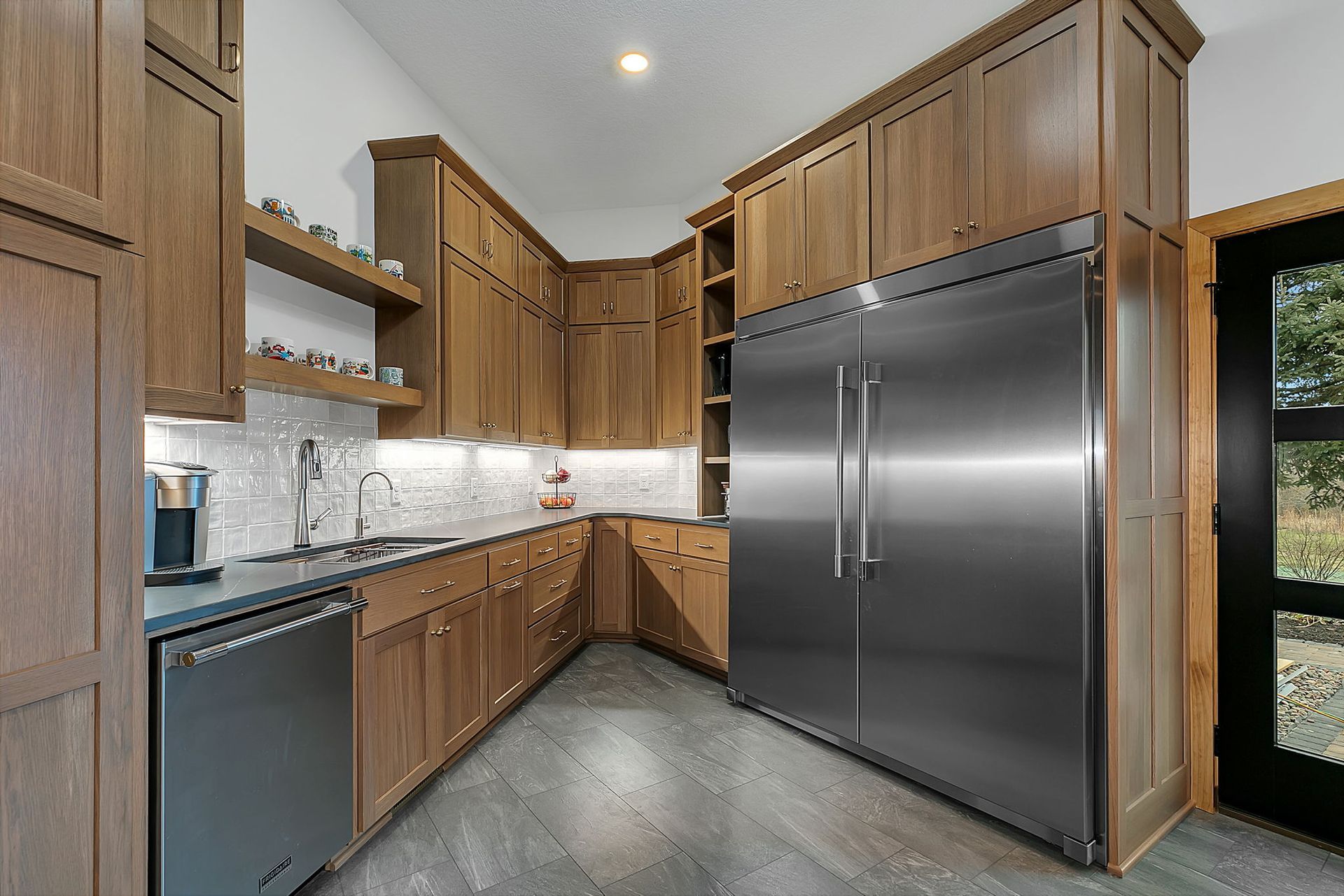Modern kitchen with wood cabinets, stainless steel appliances, and gray floor.
