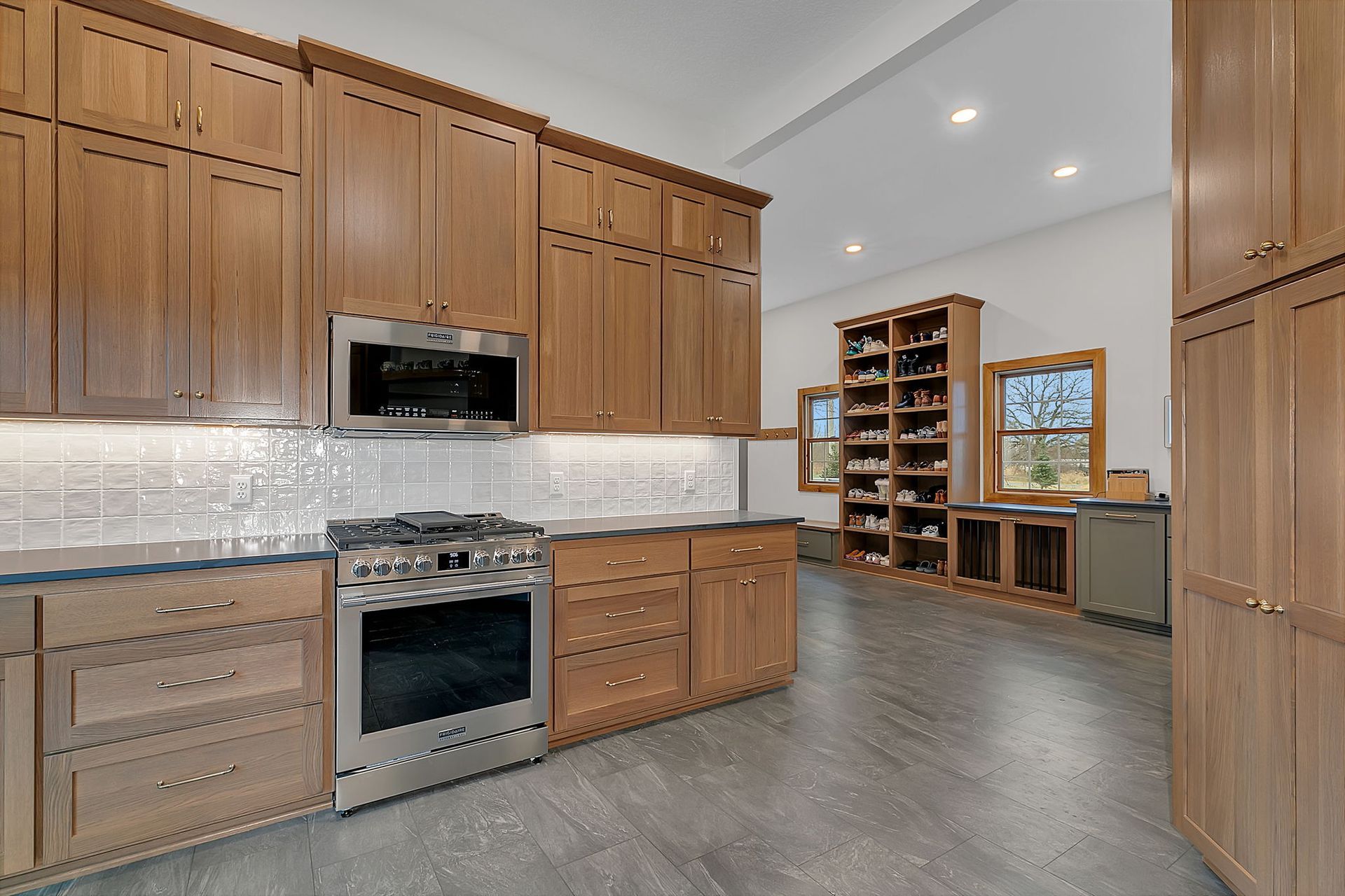 Modern kitchen with wood cabinets, stainless steel appliances, and a gray floor.