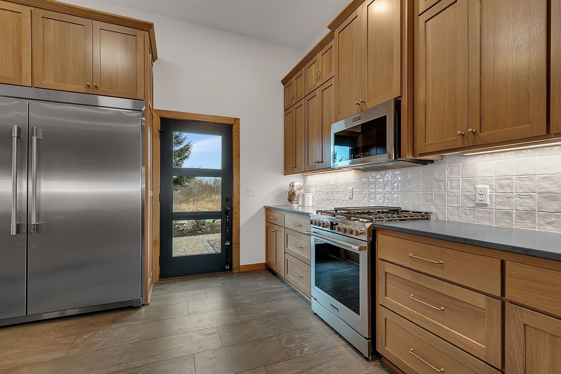 Kitchen with stainless steel appliances, oak cabinets, and a door to the outdoors.