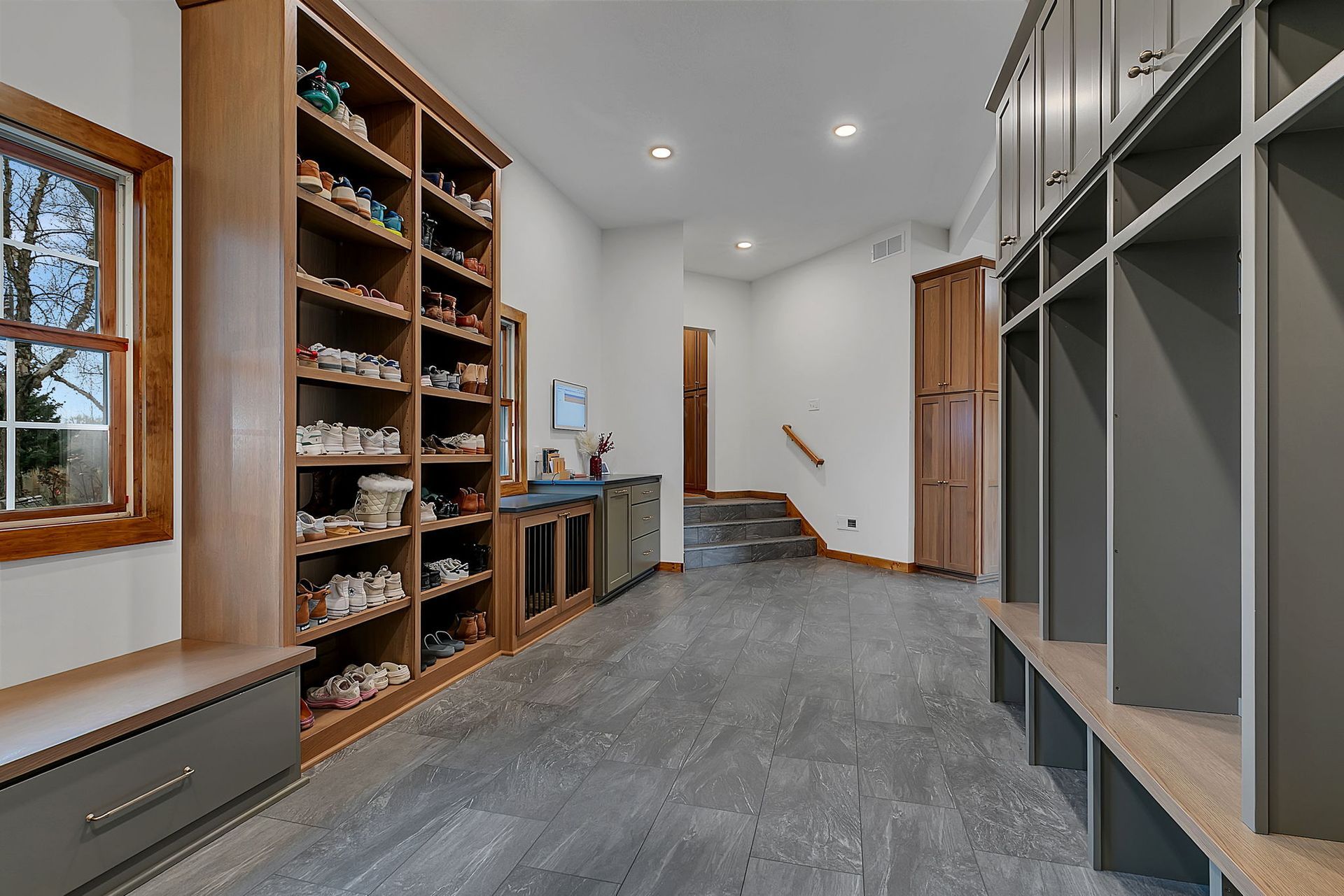 Mudroom with wooden shoe shelves, lockers, and gray tile floor.