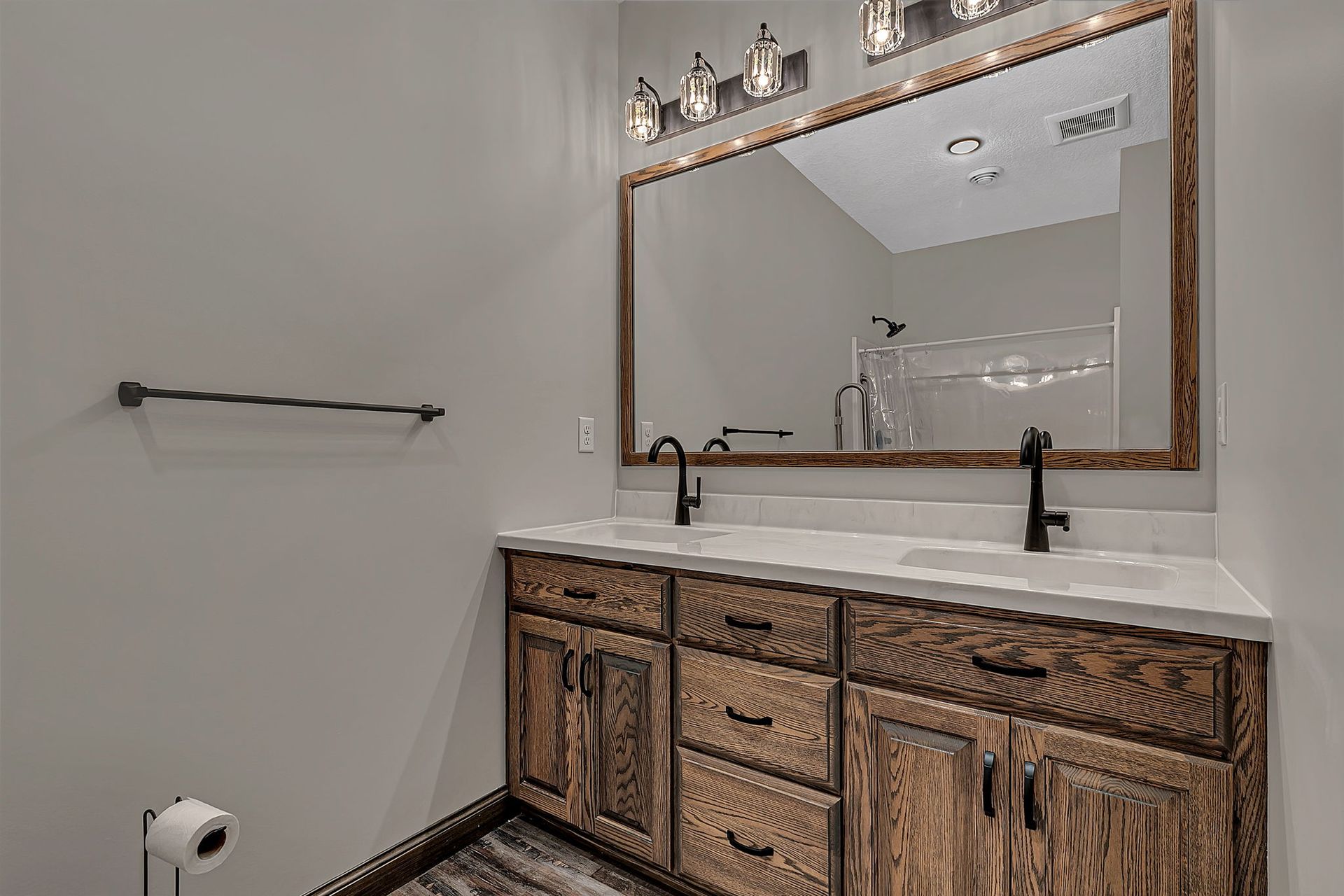 Bathroom with wood vanity, large mirror, and black fixtures.