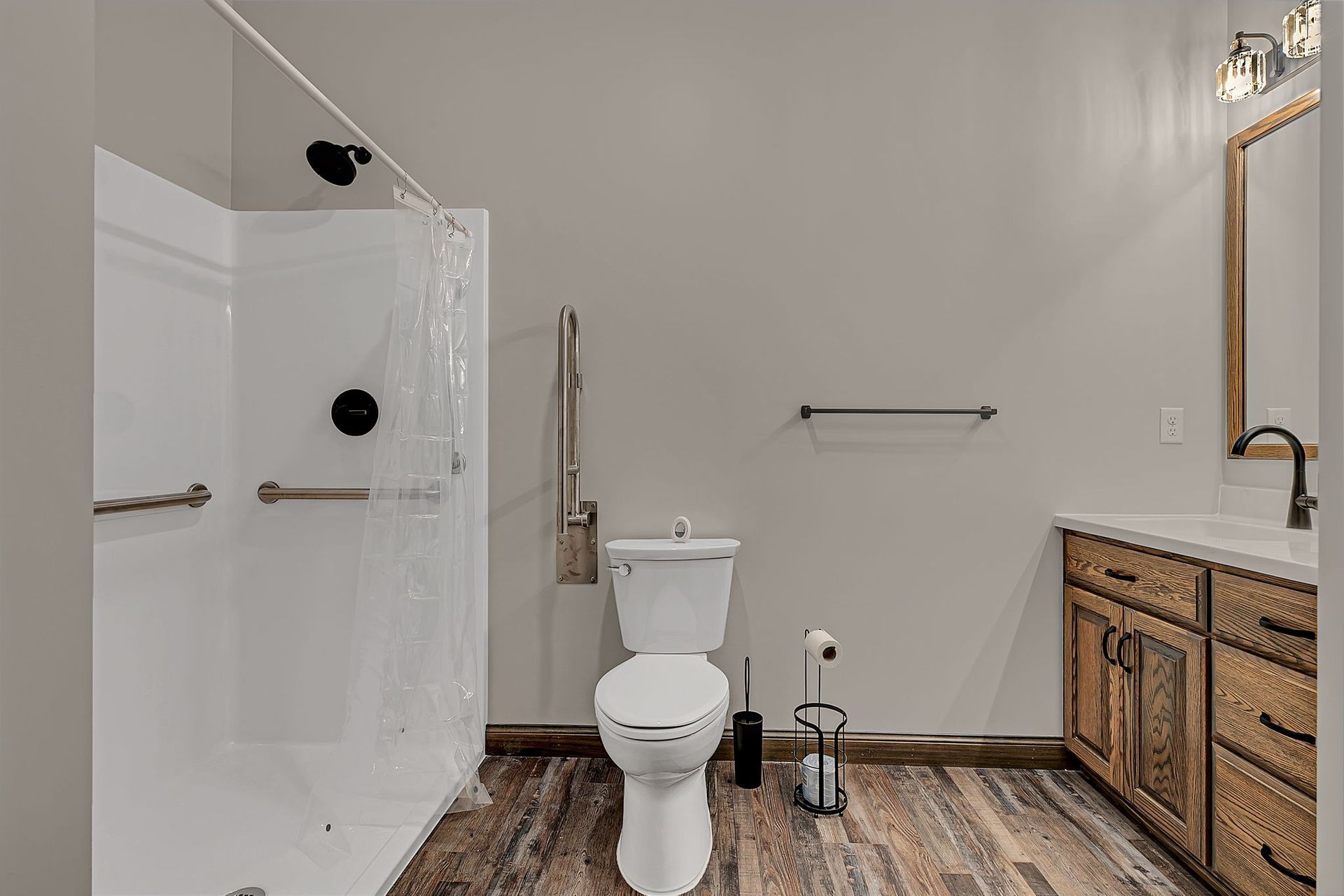 Bathroom with accessible features: shower with grab bar, toilet, vanity, neutral color scheme.