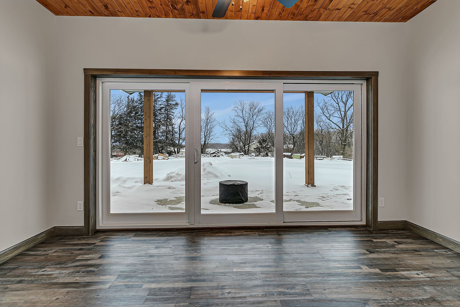 Interior view with large sliding glass doors overlooking a snowy backyard.