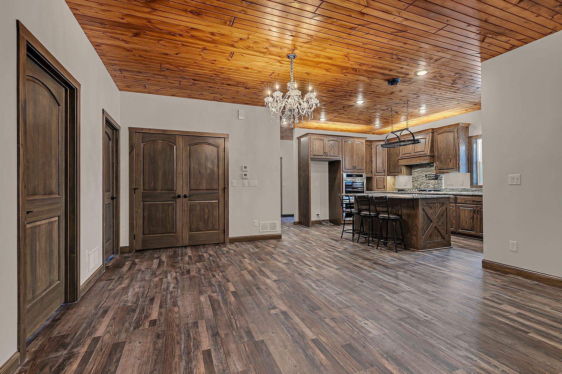 Spacious interior with dark wood floors and cabinets, kitchen island, and ornate ceiling.