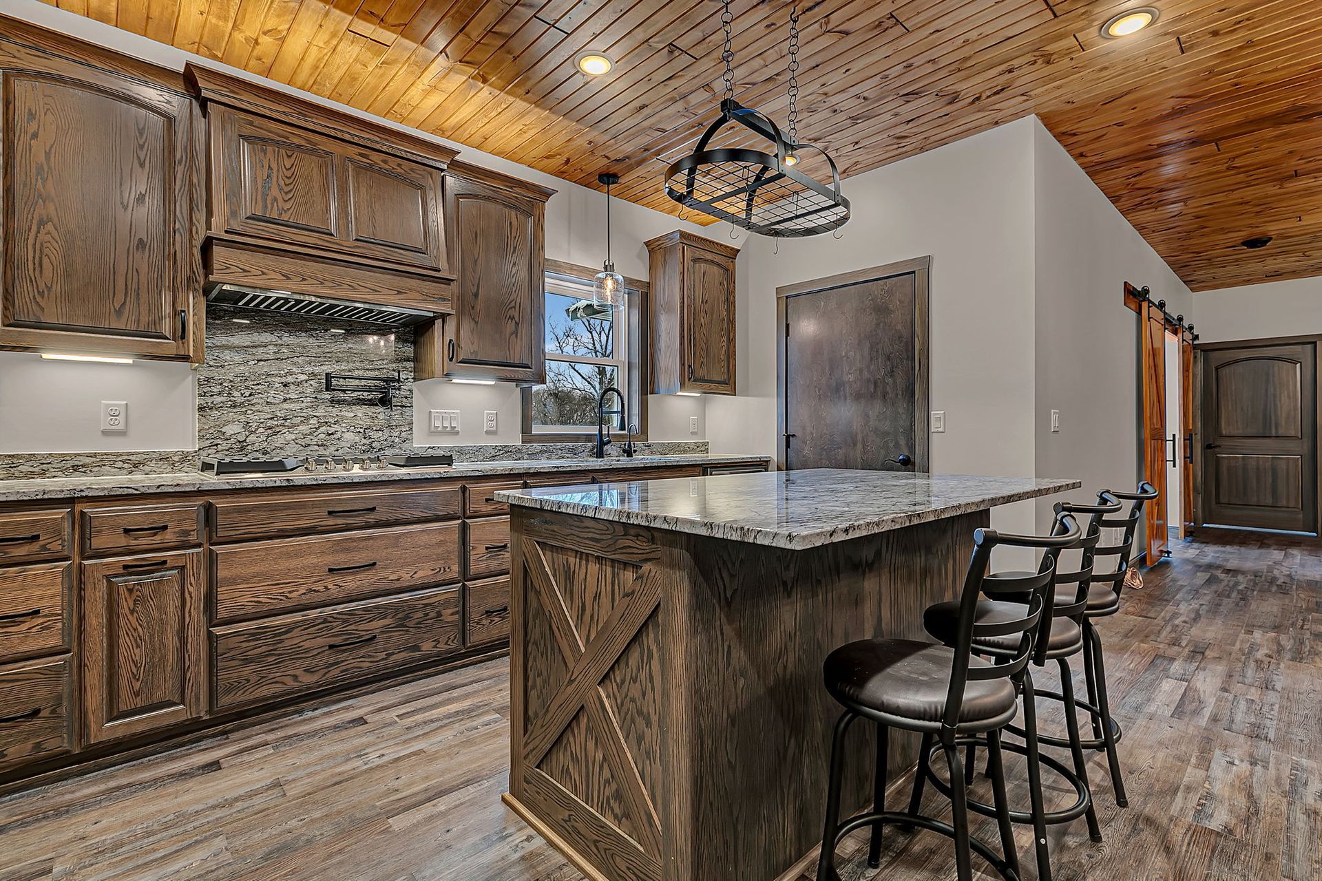 Kitchen with wood cabinets, granite countertops, and island with bar stools.