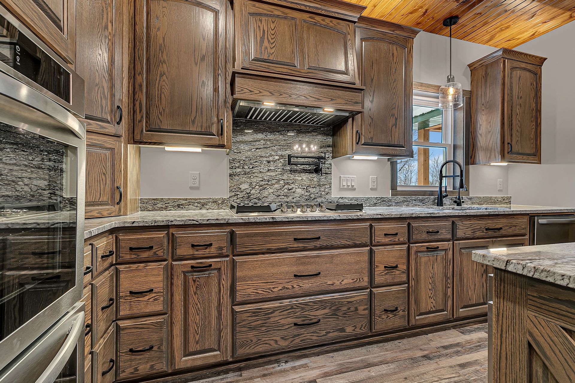 Wooden kitchen cabinets, granite countertops, tile backsplash. Modern kitchen with stainless steel appliances.