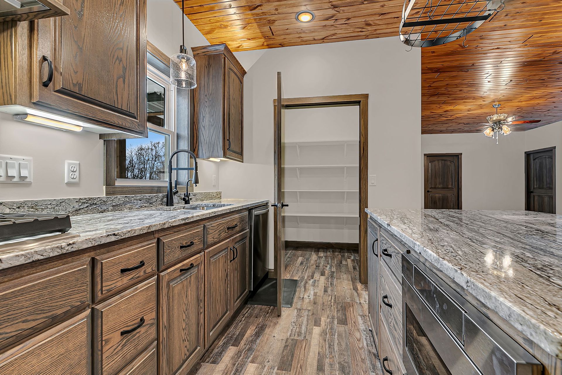 Kitchen with dark wood cabinets, granite countertops, and pantry.