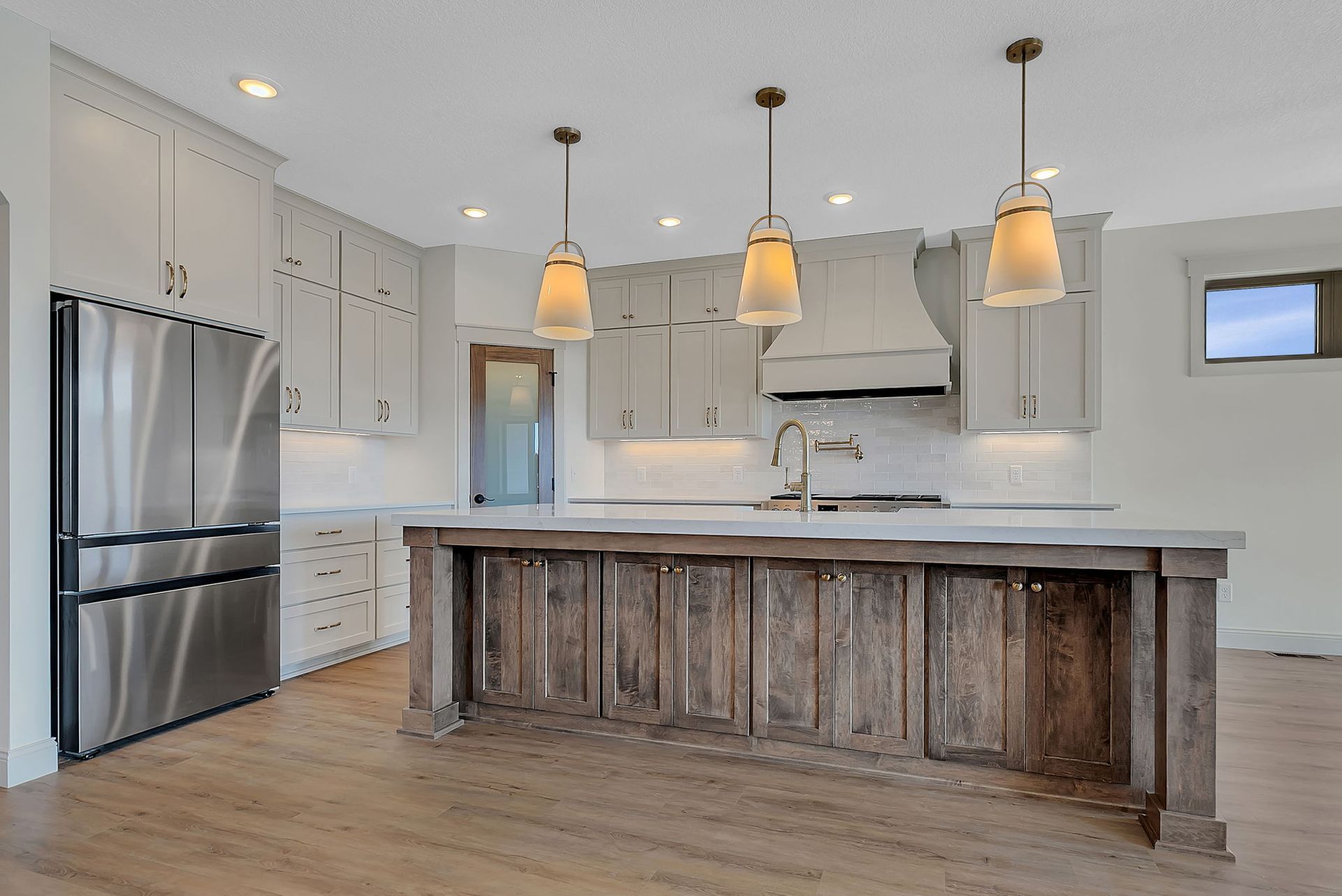Modern kitchen with wood island, stainless steel appliances, and gray cabinets.