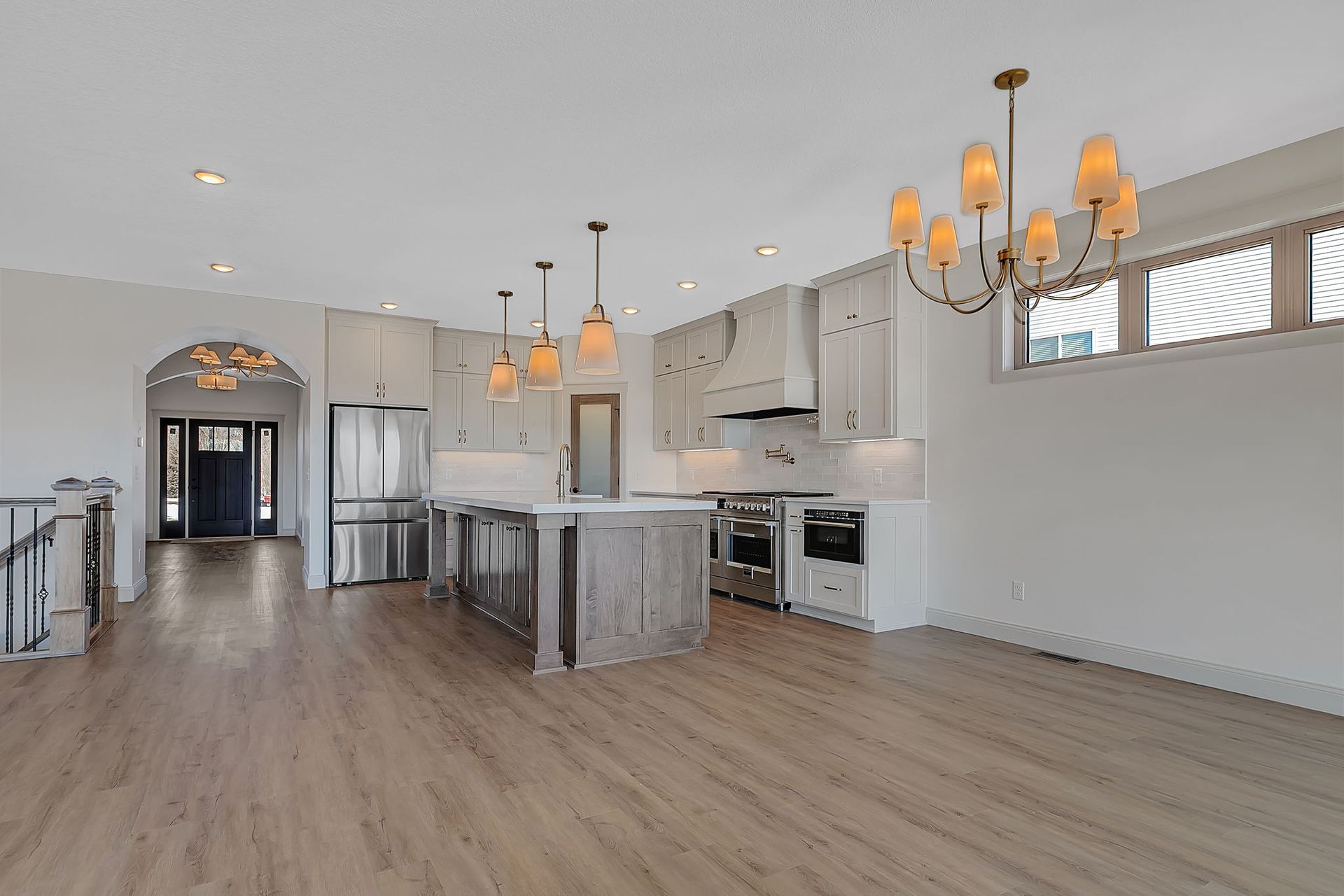 Spacious, open-concept kitchen with light gray cabinets, island, and wood floors. 