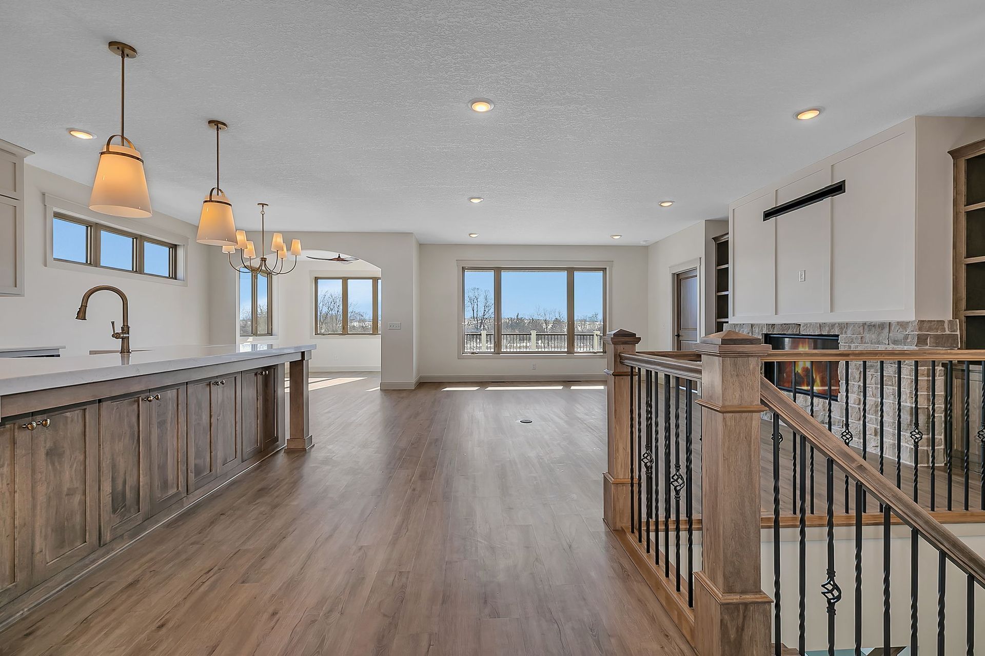 Open-concept interior with kitchen island, wood flooring, and staircase. Bright, airy, neutral color palette.