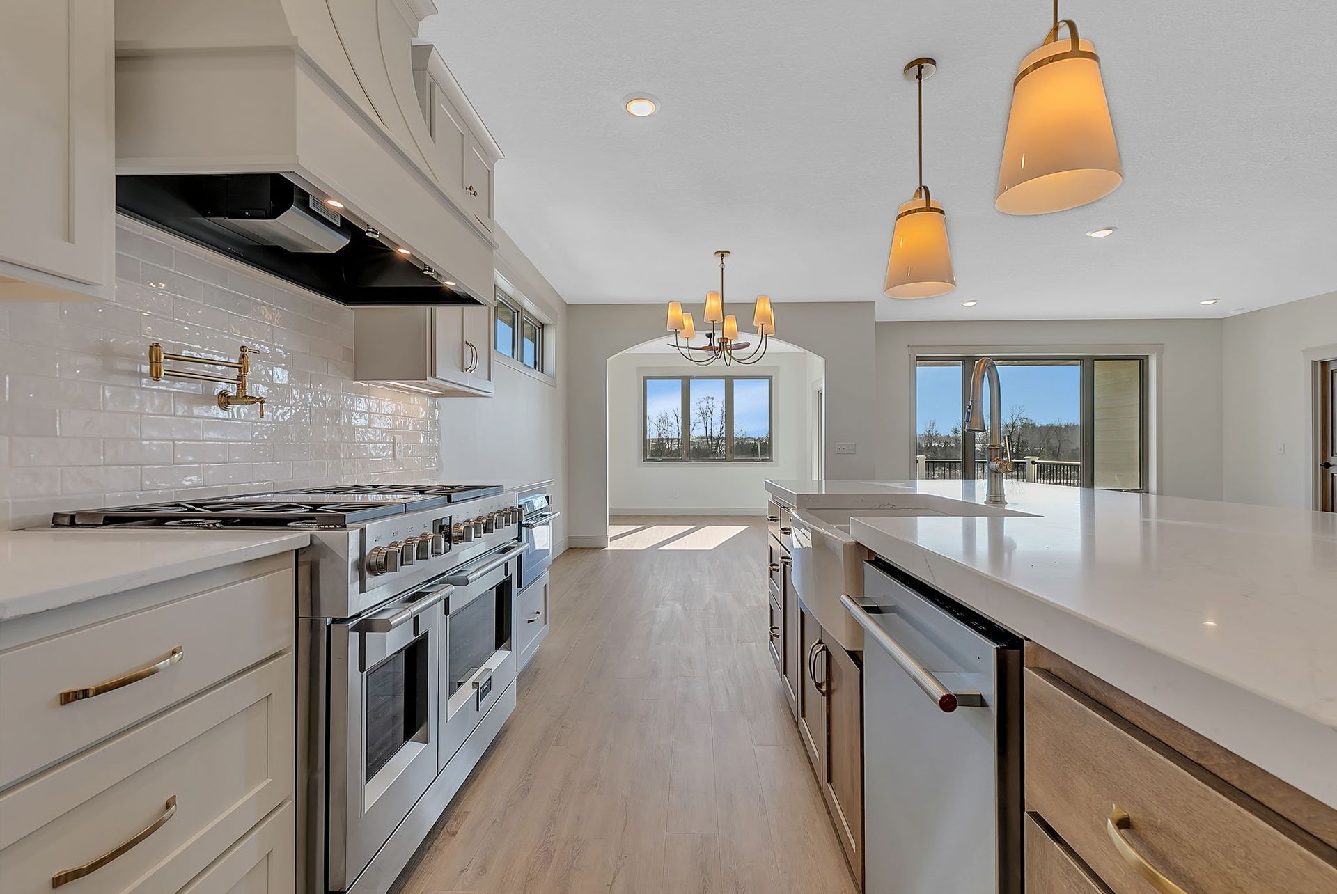 Elegant white kitchen with stainless steel appliances, marble countertops, and pendant lights.