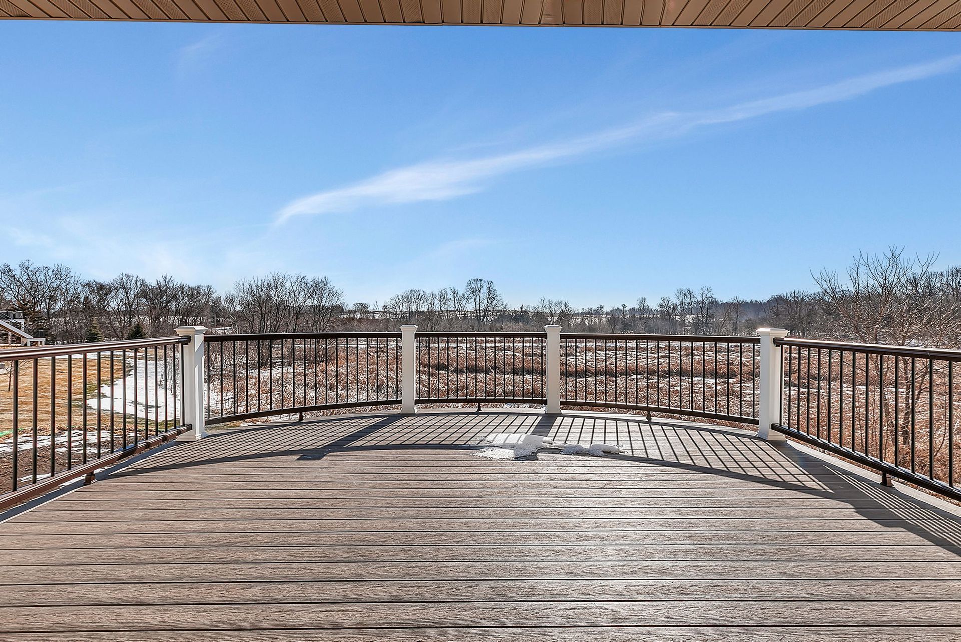 Deck overlooking a snowy landscape under a bright blue sky.